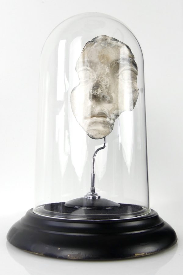 Fragment de visage en plâtre sous cloche
