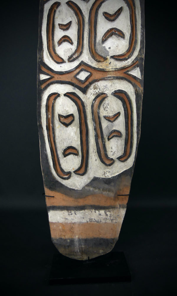 Grand bouclier de guerre Kombai en bois peint sur socle (détail face)