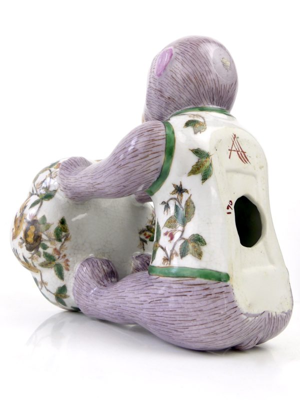 Petit singe mauve portant une coupelle en céramique (3/4 dos)