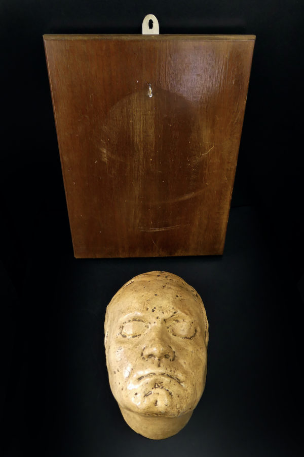 Masque mortuaire ancien en plâtre présenté sur planche de bois Mi-XXe (détail)