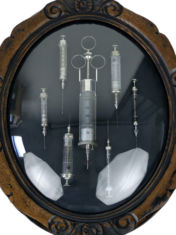 Seringues médicales anciennes cadre ovale en bois et verre bombé (détail)