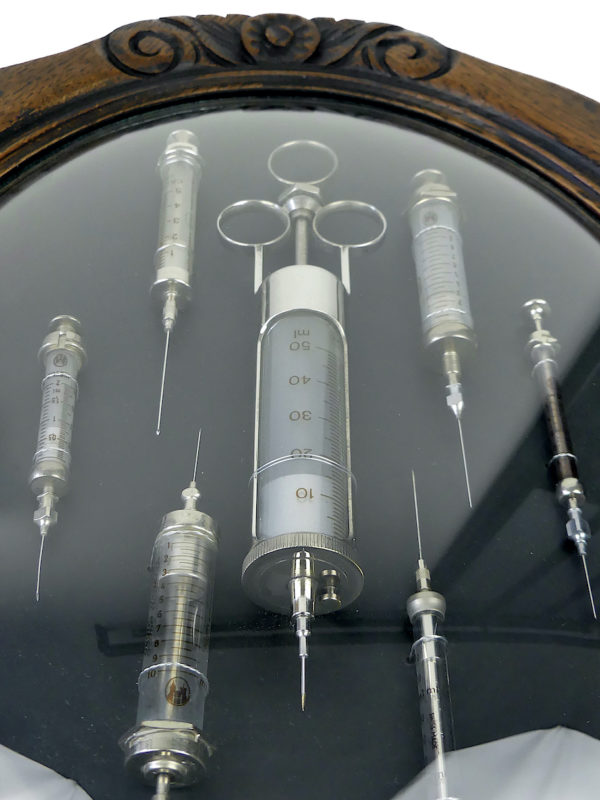 Seringues médicales anciennes cadre ovale en bois et verre bombé (détail)