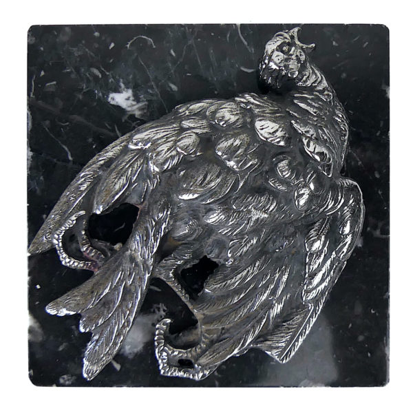 Petit oiseau mort en métal argenté sur plaque carrée de marbre noir (face)