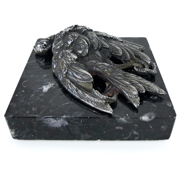 Petit oiseau mort en métal argenté sur plaque carrée de marbre noir (profil 3/4)