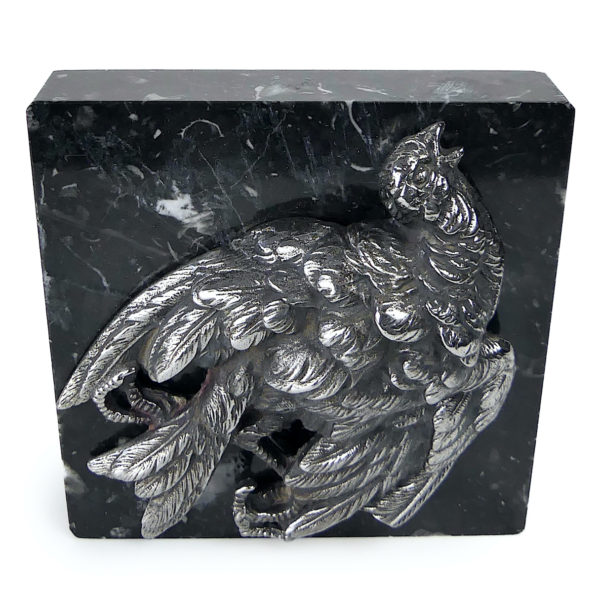 Petit oiseau mort en métal argenté sur plaque carrée de marbre noir (face)
